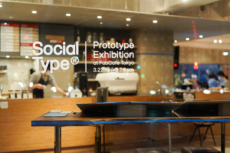 会場を窓越しに外から写した写真。窓には「Social Type Prototype Exhibition」の文字ステッカーが貼ってある