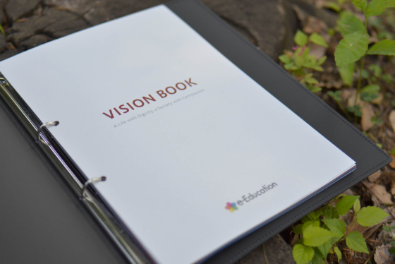 NPO法人e-Educationの社員向け冊子飲み開きの写真。ページには「VISIONBOOK」と記載されている。