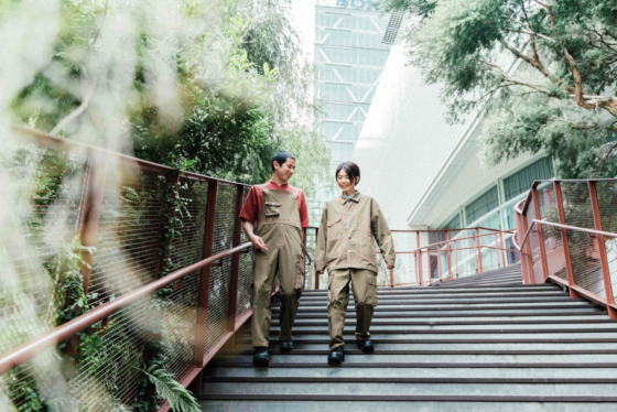 コクヨのTHE CAMPUSの入り口。さまざまな種類の木々の中、SOLITがデザインしたユニフォームを着用する二人。